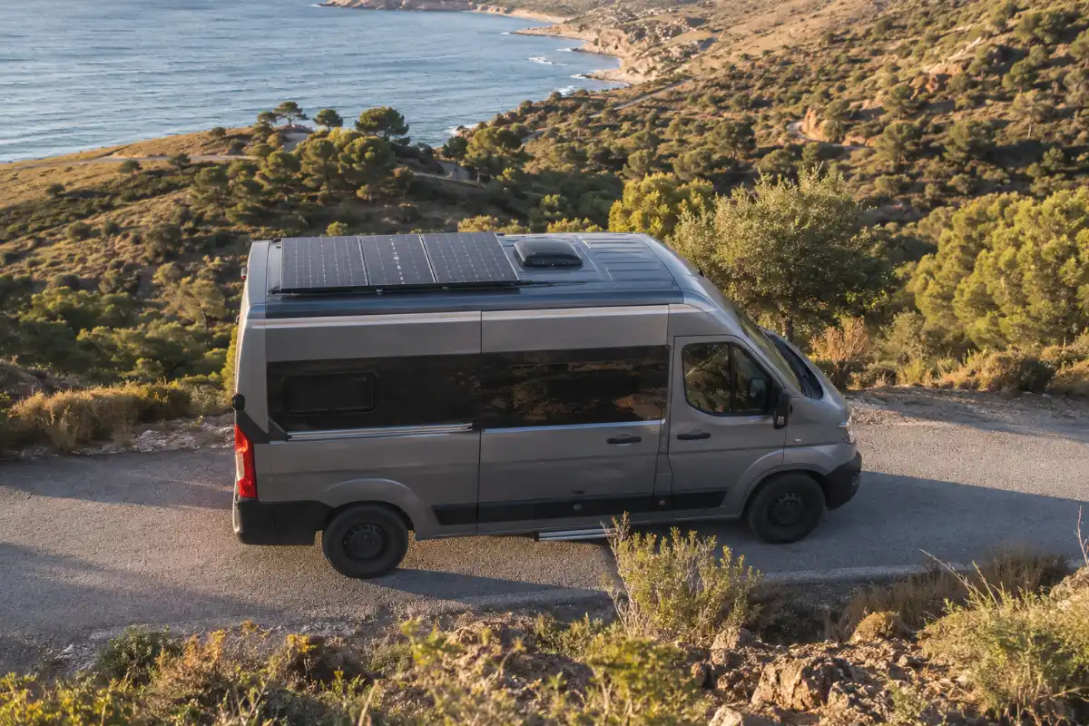 Placas solares 4 Furgoneta camperizada con paneles solares visibles en el techo, vista lateral cerca de la playa homologar camper placas solares