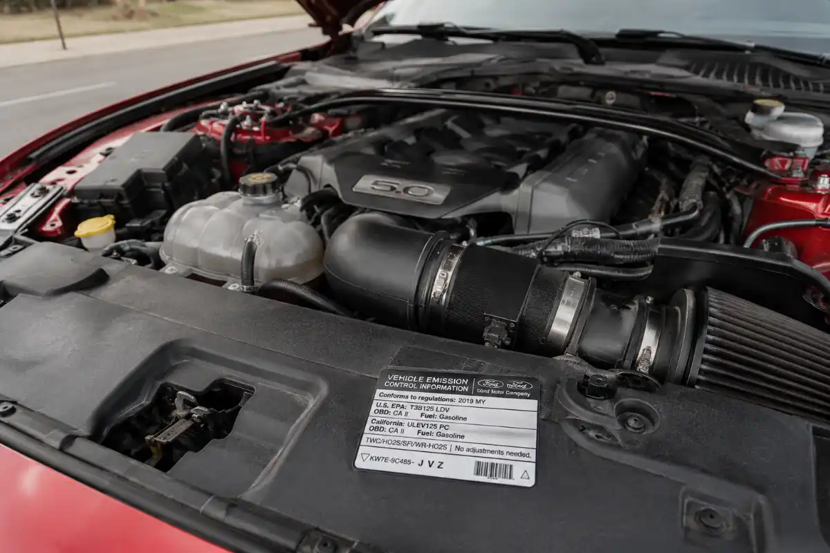 Importar un Mustang de USA: guía completa 4 Motor V8 Mustang con placa de emisiones visible en compartimento del motor a importar mustang usa españa
